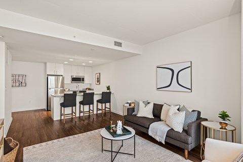 A modern living room with a grey couch, a coffee table, and a dining table with chairs.
