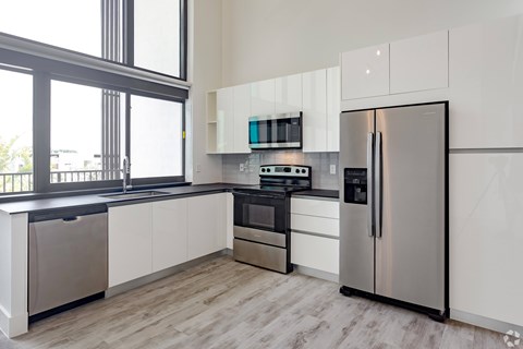 a kitchen with white cabinets and stainless steel appliances and a window