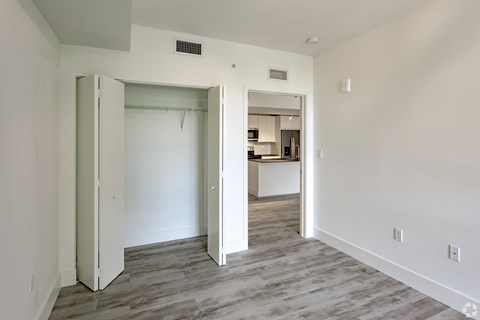 a bedroom and a living room with white walls and wood flooring