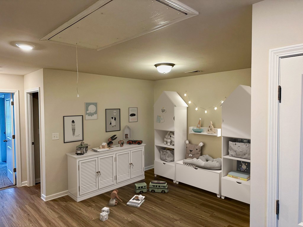 a nursery with a white dresser and a crib and a play area with lights