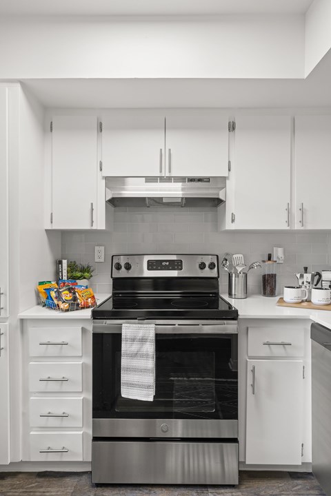 A modern kitchen with a stainless steel oven and white cabinets.