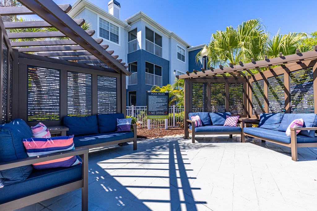 a patio with blue couches and a wooden pergola