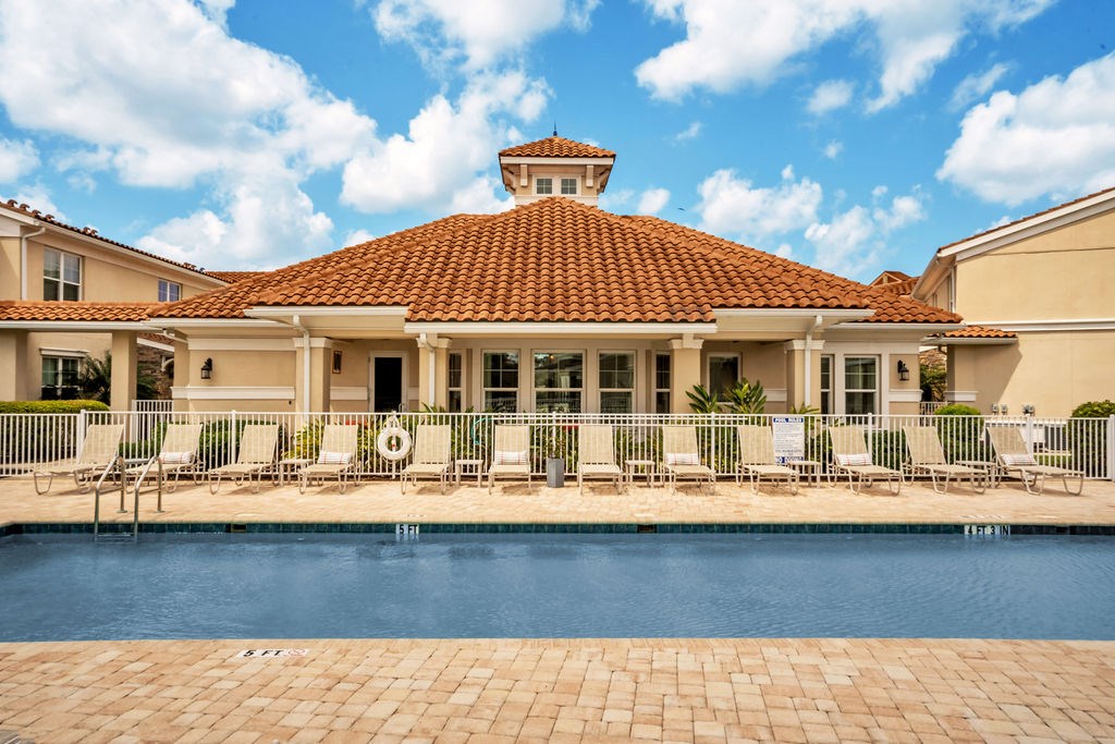 a house with a pool and chairs in front of it
