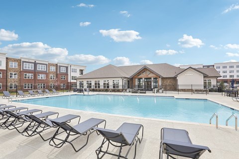 A pool with sun loungers in front of a building.