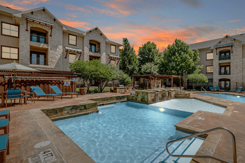 A large swimming pool surrounded by lounge chairs and trees.