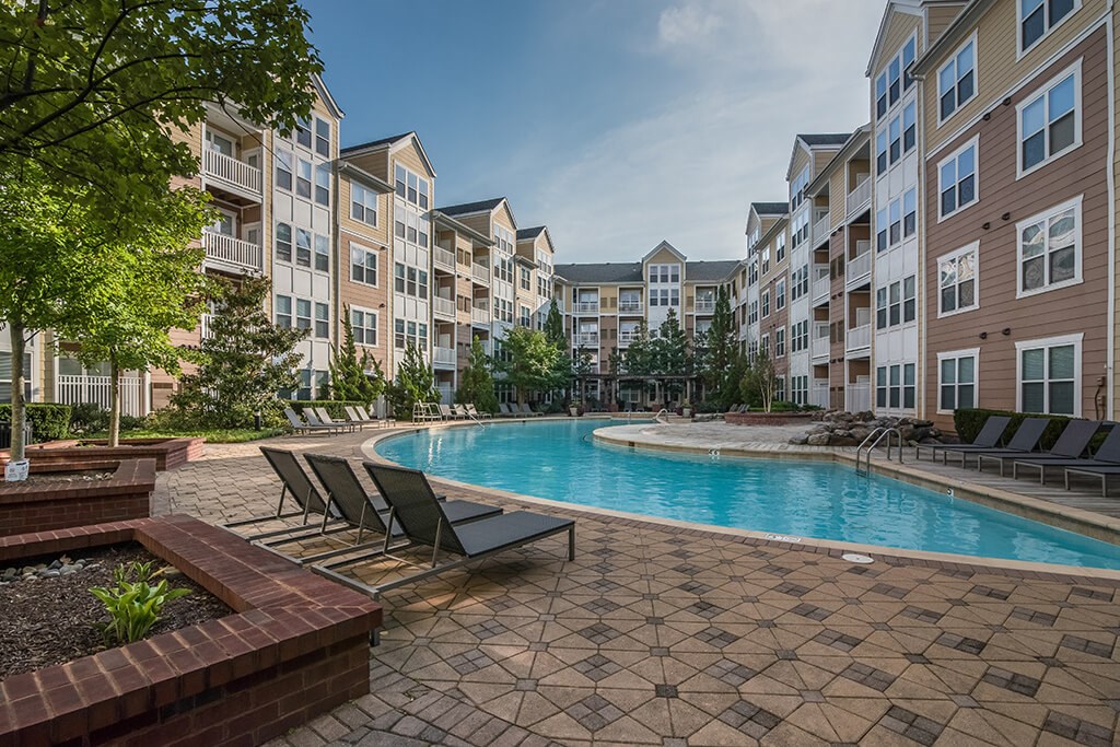 an apartment building with a pool and lounge chairs
