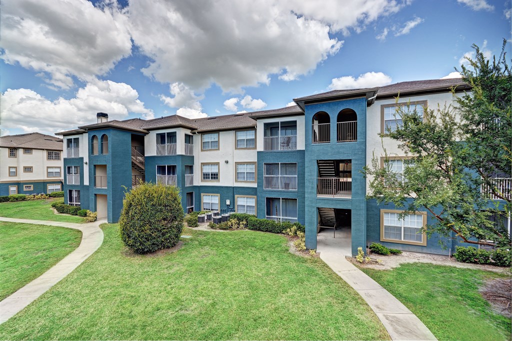 an apartment building with green grass and a sidewalk