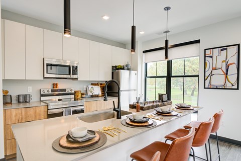 A modern kitchen with a dining table set for two.