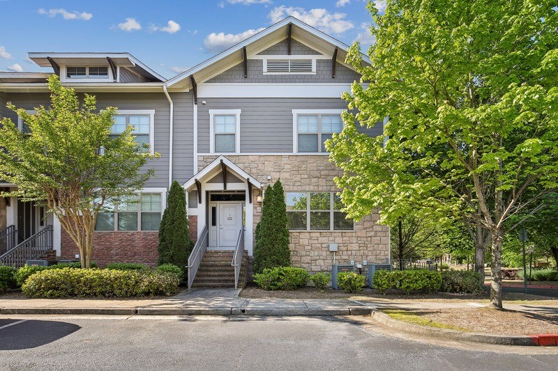 front view of an apartment building with stairs and trees