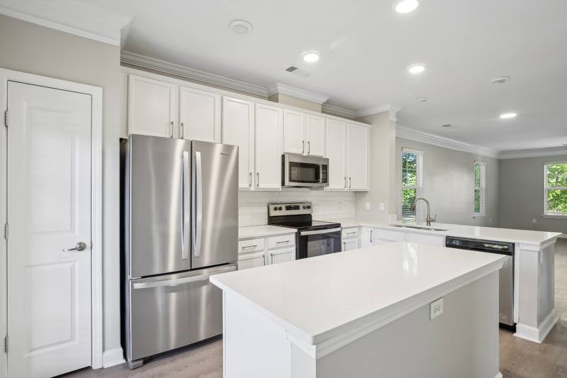 a large white kitchen with a stainless steel refrigerator