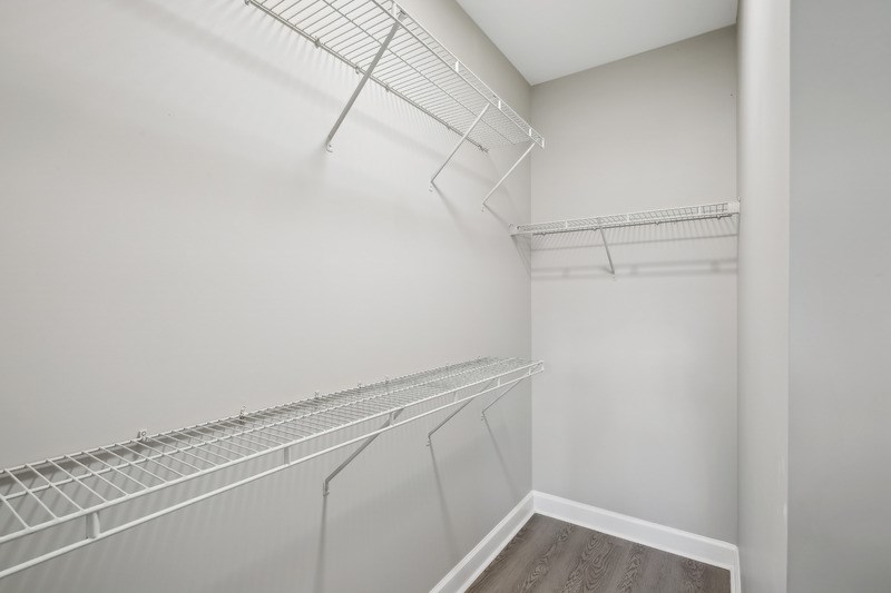an empty closet with white walls and shelves and a wood floor