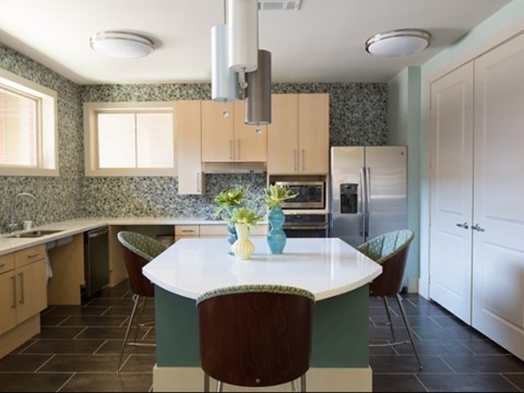 A kitchen with a table and chairs in the middle.
