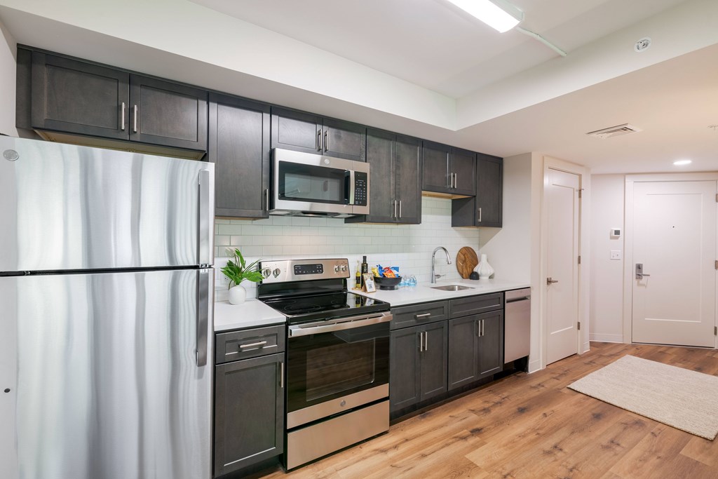a kitchen with black cabinets and stainless steel appliances and a refrigerator
