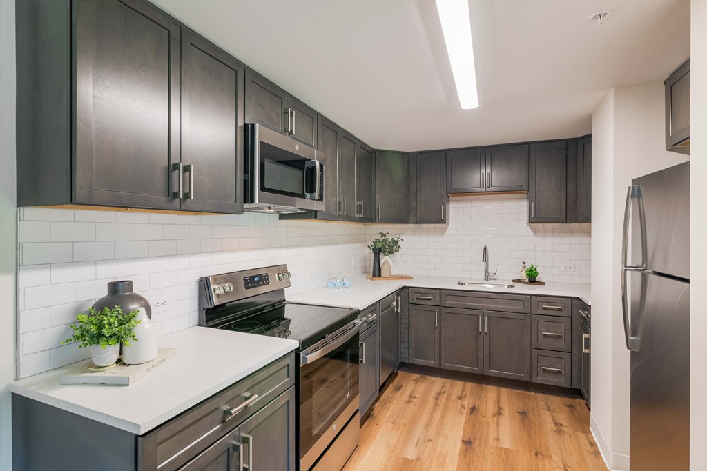 a kitchen with black cabinets and stainless steel appliances and white countertops