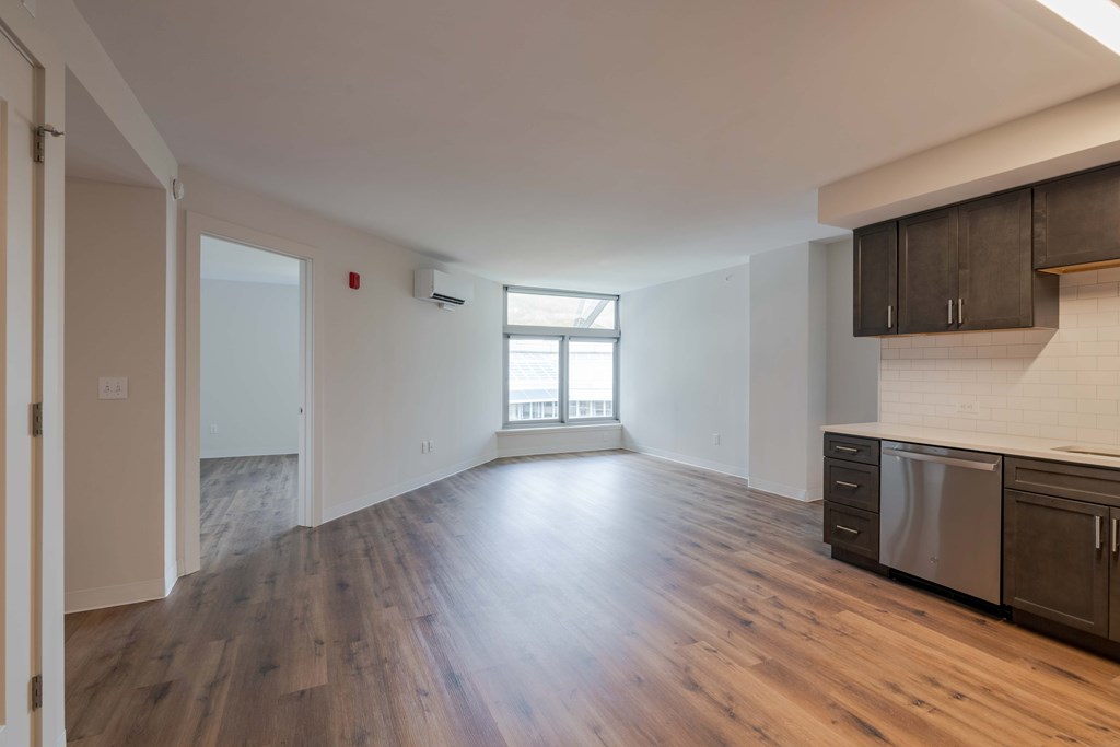 an empty living room with wood flooring and a window