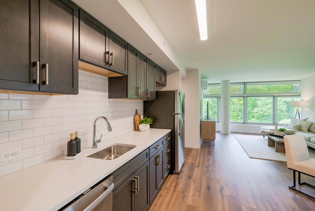 a kitchen with dark cabinets and a white counter top and a sink