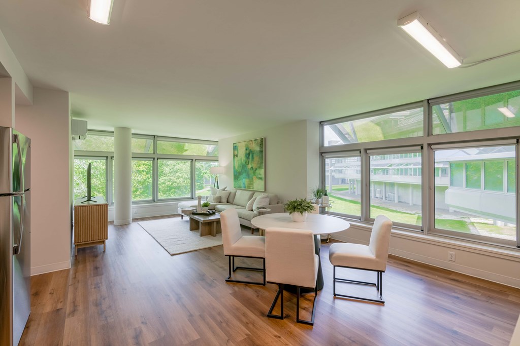 a living room with a table and chairs and large windows