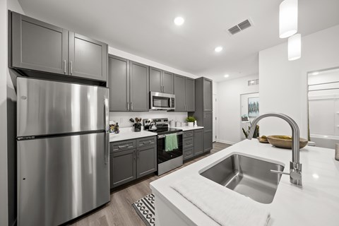 A modern kitchen with a stainless steel refrigerator and a white countertop.