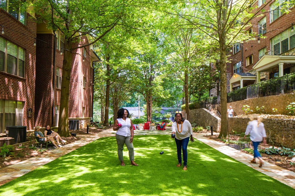 people walking on a lawn in front of houses