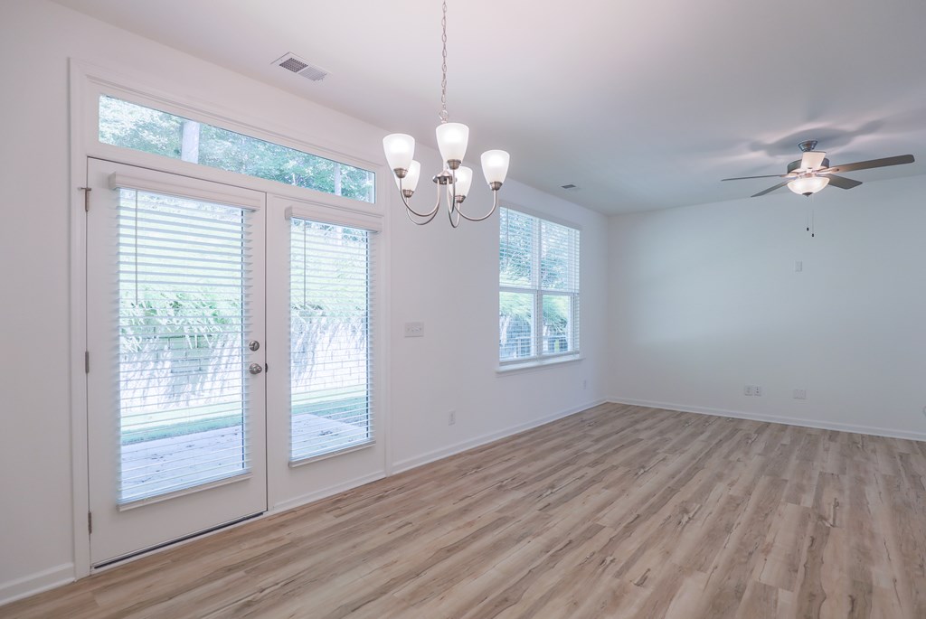 an empty living room with windows and a ceiling fan