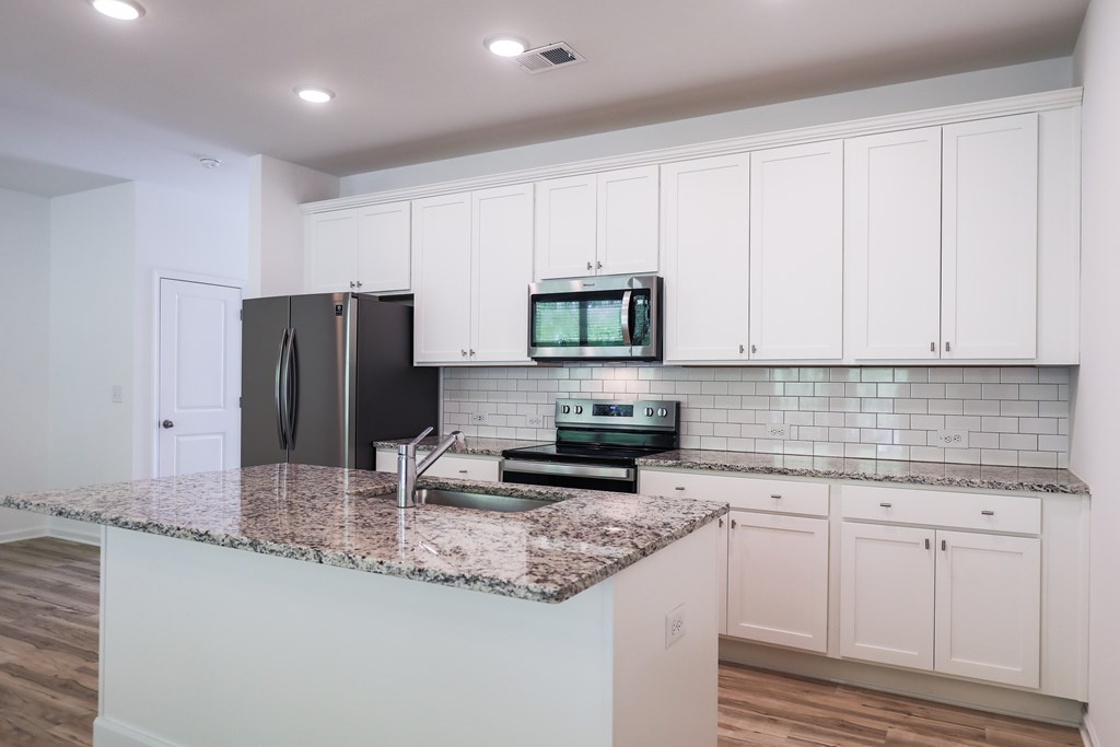 a kitchen with white cabinets and a granite counter top