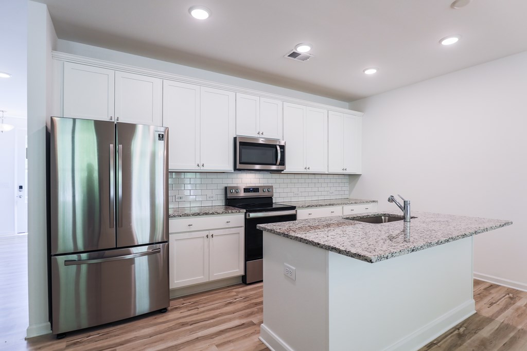a kitchen with a granite counter top and stainless steel refrigerator