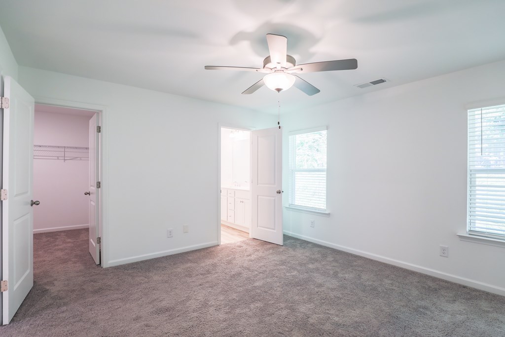 an empty living room with a ceiling fan and a closet