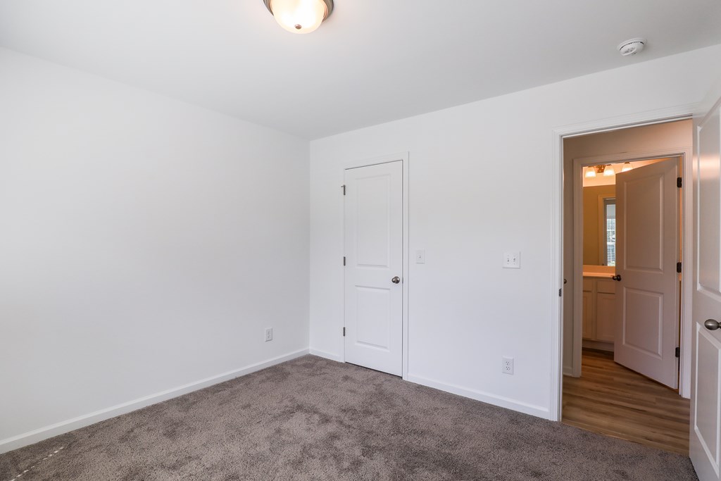 a living room with white walls and a door to a closet