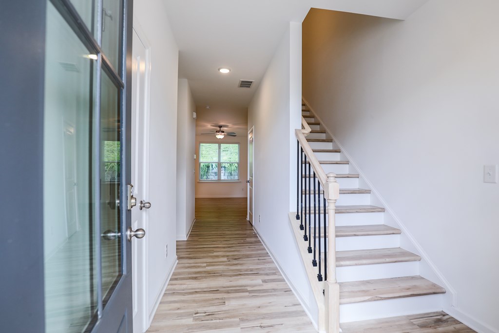 a long hallway with stairs and a glass door