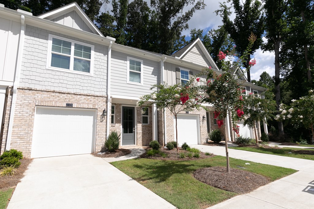a white house with two garage doors and a lawn