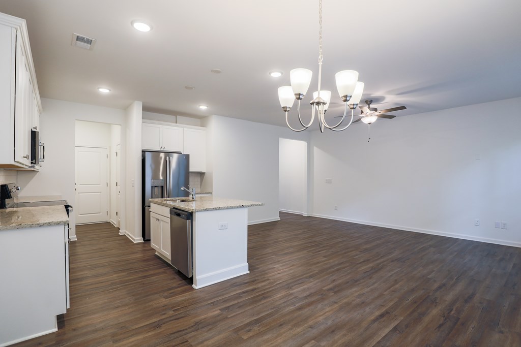 a living room with a kitchen and a chandelier