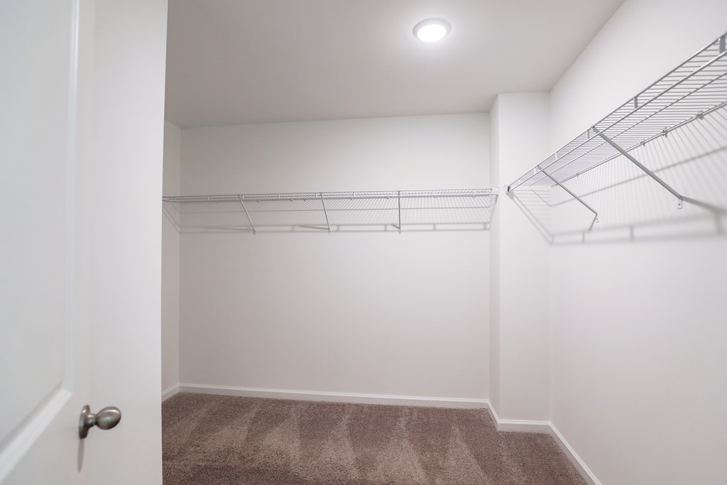 a room with white walls and a closet with wire shelving