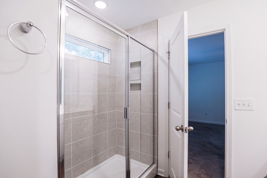 a shower with a glass door in a white bathroom