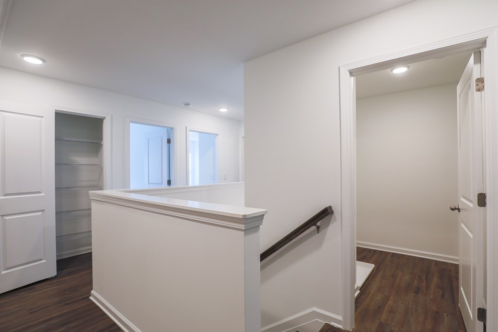 a corridor with white walls and a white staircase with a white counter and a door