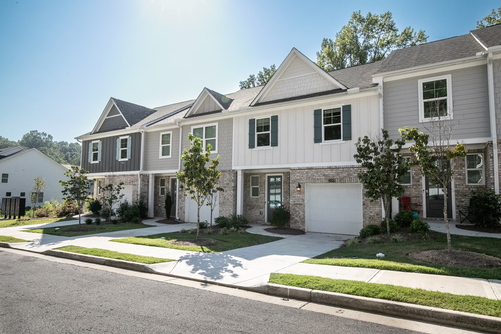 a white and brick house with a street in front of it