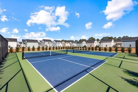 A tennis court surrounded by houses and trees.