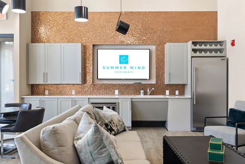 A living room with a couch, chairs, and a television displaying the words "Summer Wind".