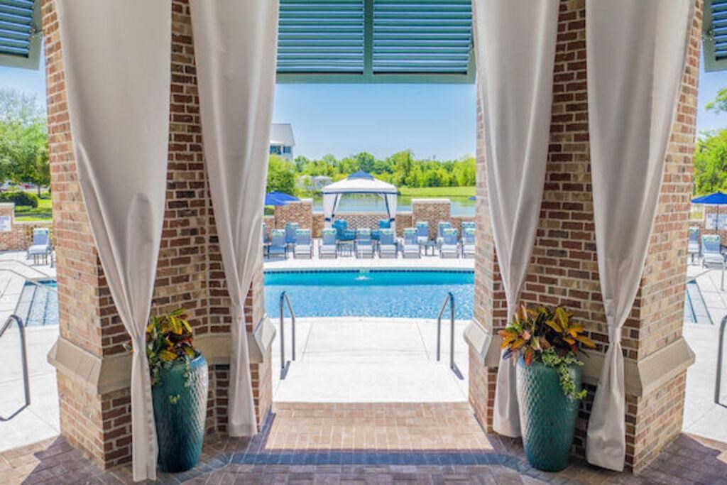 a view of a pool from a covered porch with white drapes and curtains