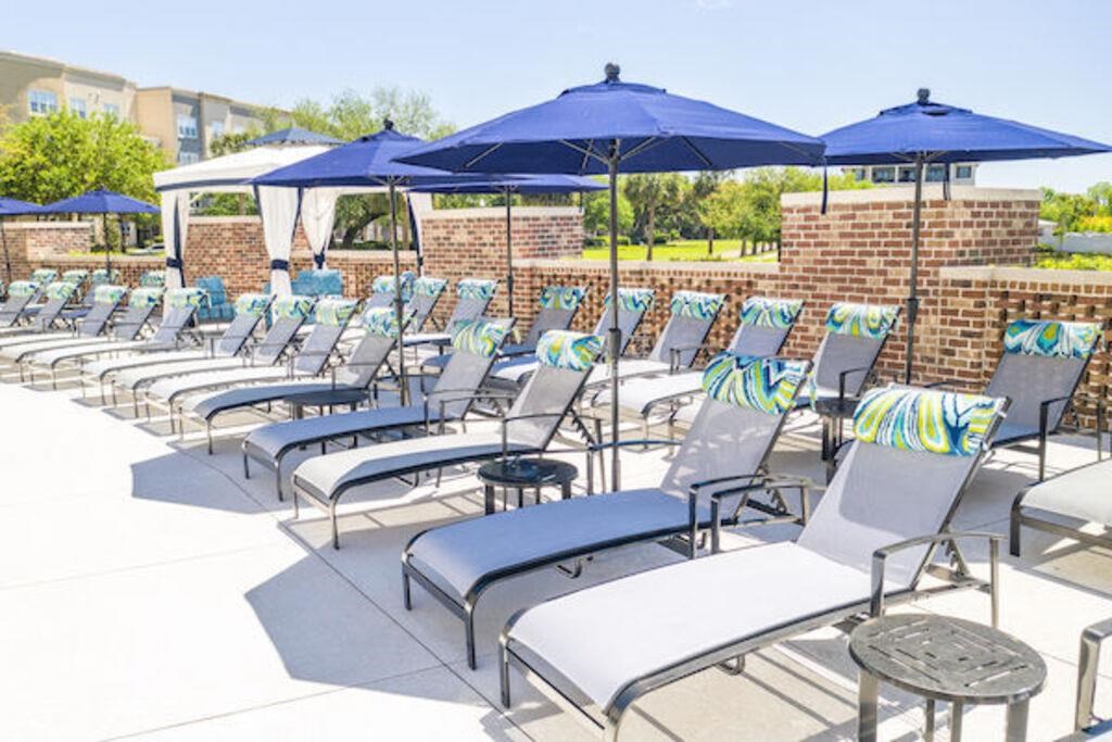 a row of lounge chairs with umbrellas on a patio