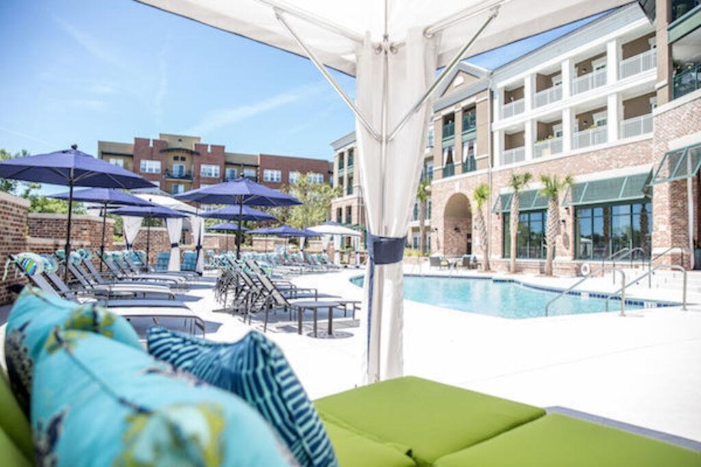 a pool with lounge chairs and umbrellas in front of a building