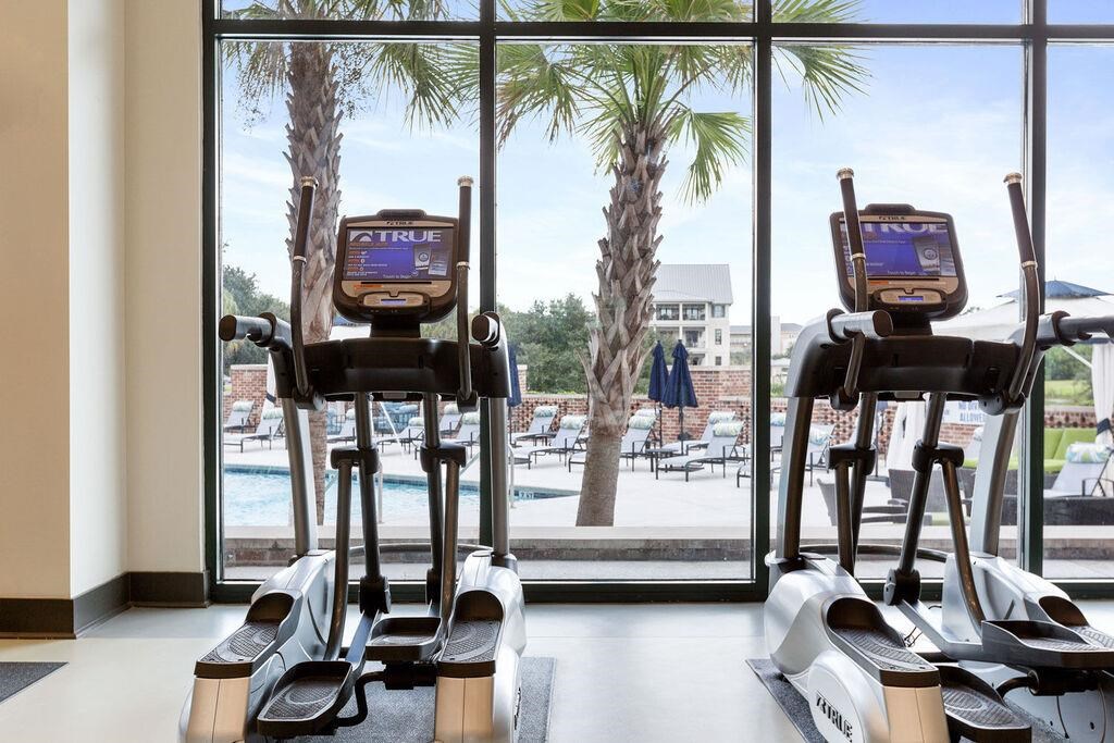a gym with a view of the pool and palm trees