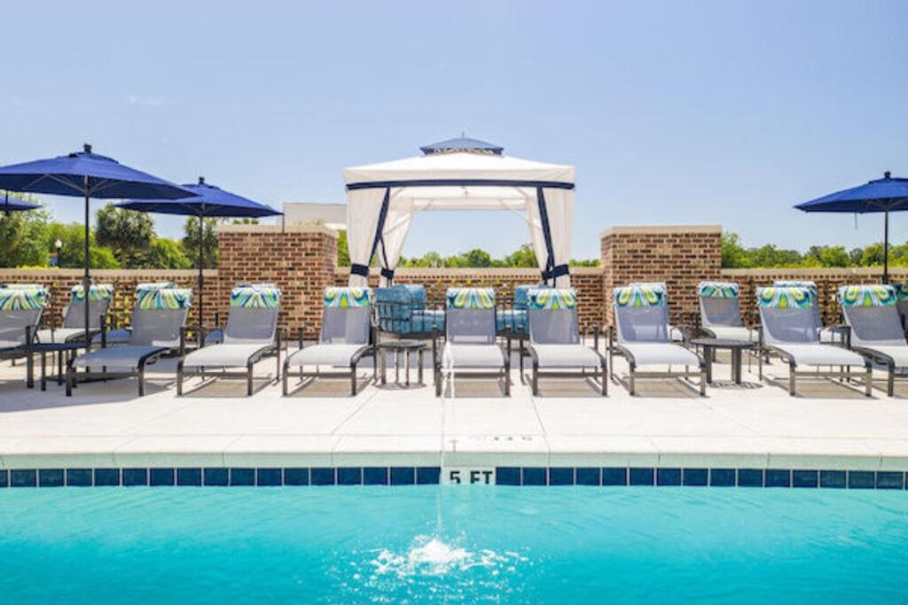 a swimming pool with chairs and umbrellas next to it