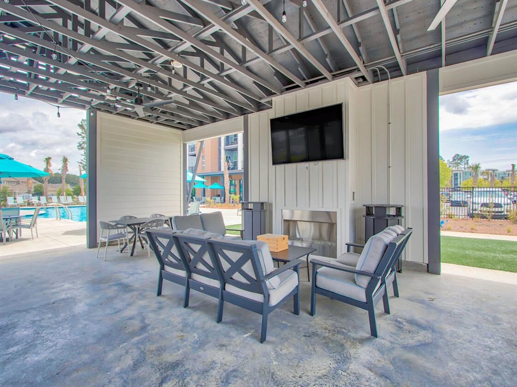 a patio with a fireplace and chairs and a tv