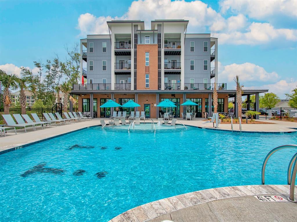 a large pool with chairs and umbrellas in front of a building