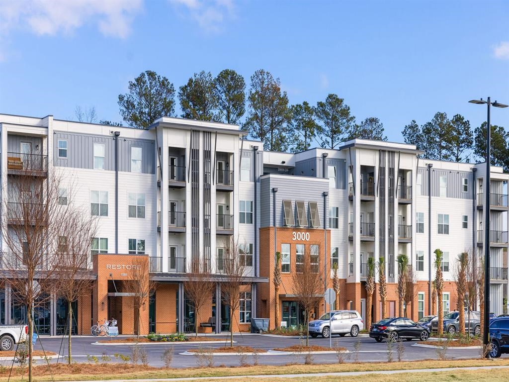 a street view of an apartment building with cars parked in front