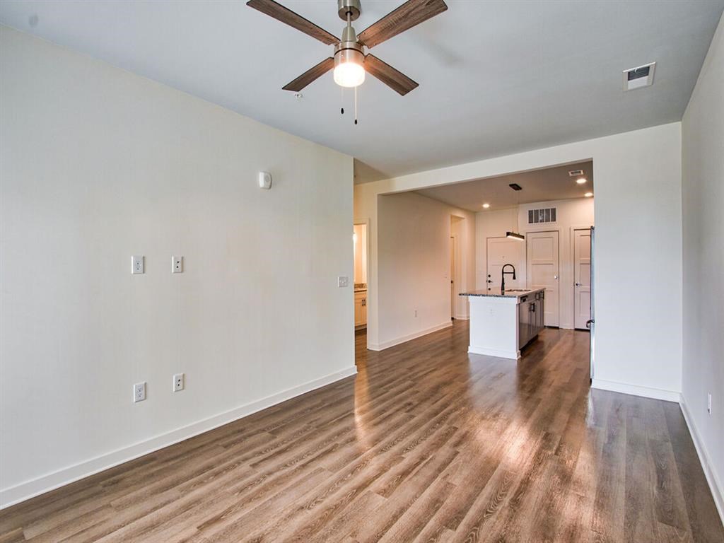 an empty living room with a ceiling fan and a kitchen