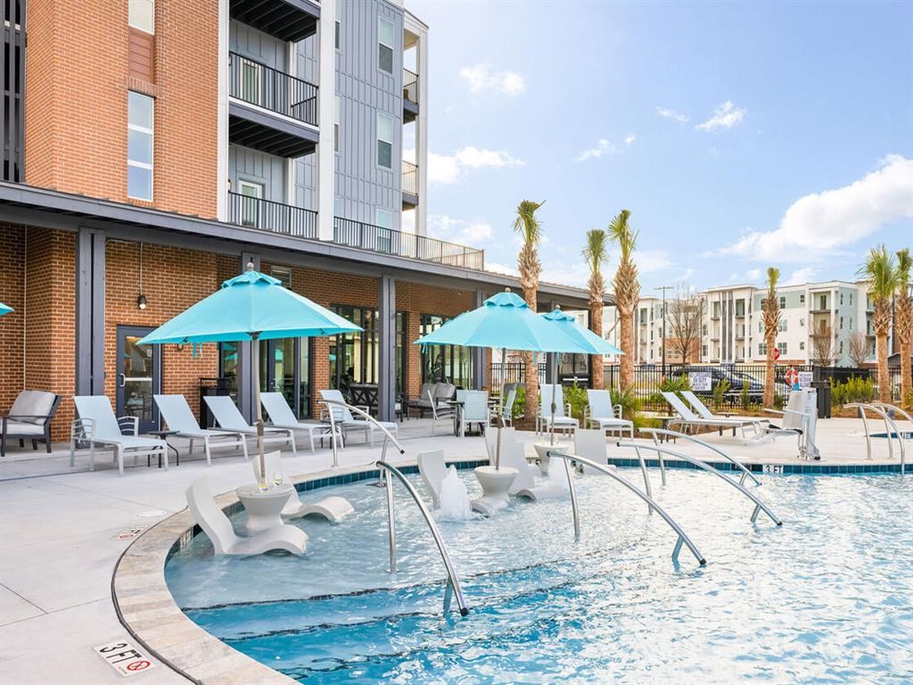a swimming pool with chairs and umbrellas next to a building