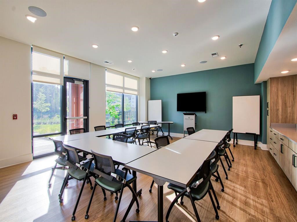 a conference room with a table and chairs and a television