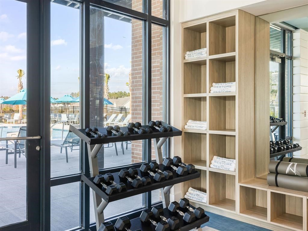 a gym with weights on a rack next to a window