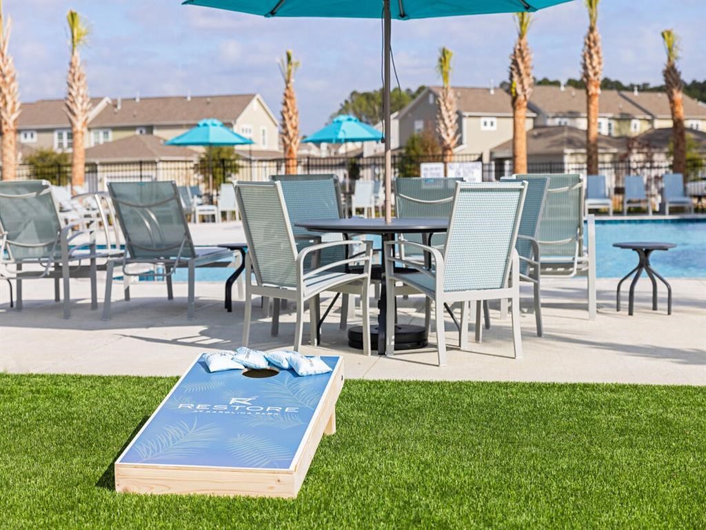 a patio with tables and chairs and a pool with umbrellas